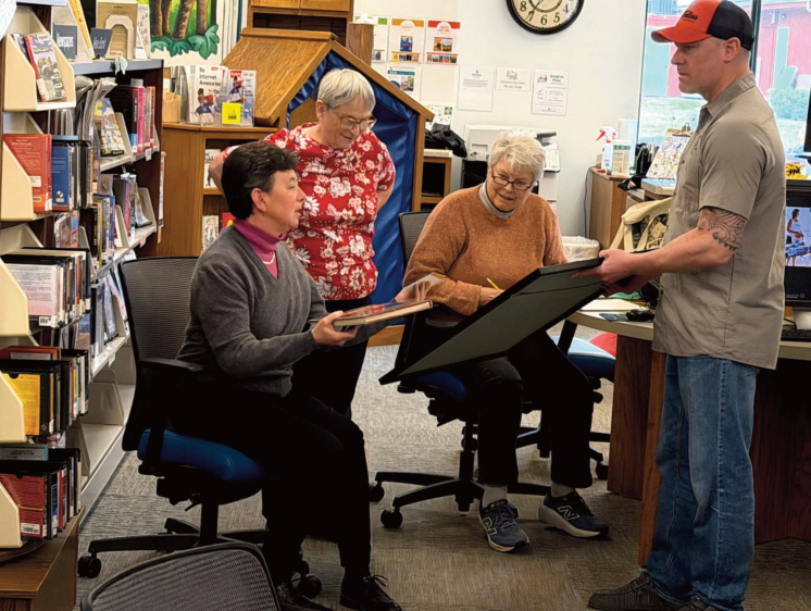 Blanchardville Historical Society officers (L-R) Becky Johnson, Bev Ryan and Judy Watrud review some Cruis'n Wisconsin Car Show memorabilia, as displayed by show organizer Aaron Jorenby. Photo by Gary Mckenzie.