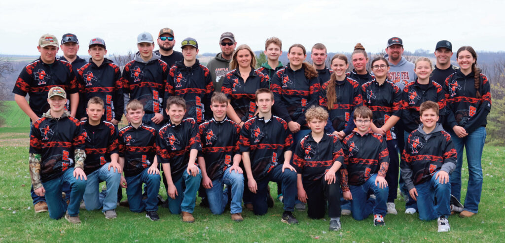 Row 1: Hayden Montgomery, Hunter Holmes, Bryar Slater, Brayden Lee, Bryce Slater, Grant Kuberski, Camden Johnsrud, Bryant Johnson, Cedar Flannery. Row 2: Gunner Stamm, Mitchell Johnsen, Wyatt Peterson, Gunner Gerber, Brinley Meinert, Elena Chenous, Emma Johnsen, Elaina Pederson, Faith Montgomery, and Ivy Flannery. Row 3: Assistant Coach Cody Crist, Coach Andy Chenous, Assistant Coach Matt Stamm, Owen Chenous, Riley Holmes, Claire Holmes, Assistant Coach Dennis Johnsen, Assistant Coach Travis Holmes.