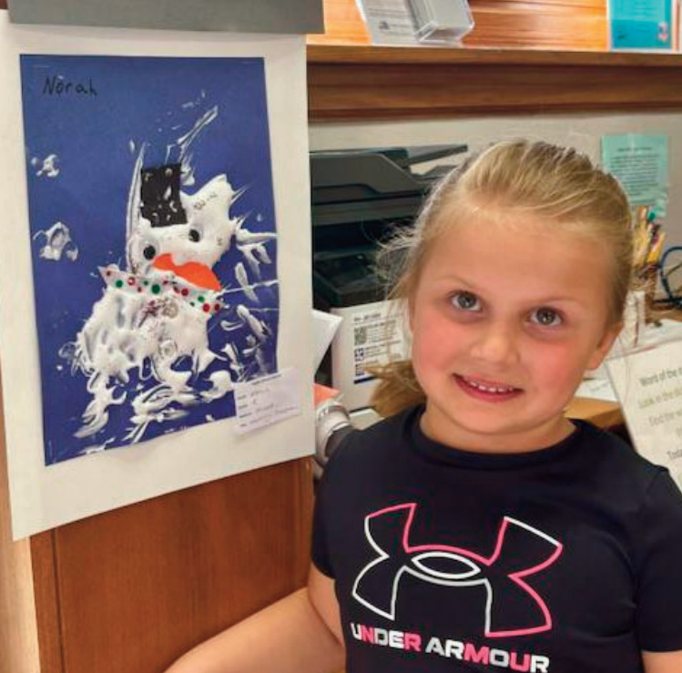 Norah, a kindergartener, created a piece titled Melting Snowman in a two-stage process. She began with combining glue and shaving cream to form the snowman itself, giving the artwork a puffy look and a three-dimensional quality. Norah then added paint, eyes, glitter, and ribbon details, sinking them into the wet white paint, before letting it dry. She said she likes how the texture of the snowman "makes it fun to look at."