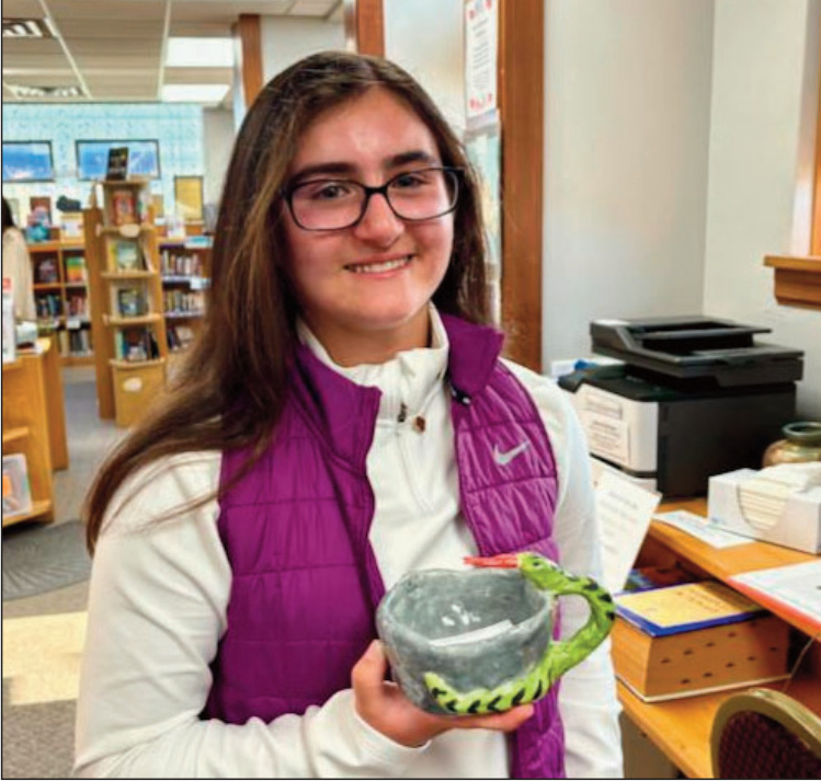 Elaina, Grade 8, created a ceramic piece titled Snake Mug as part of an assignment to "reinvent the mug." She began by forming the main gray section before deciding what to add next. She chose to design a handle in the form of a brilliant green snake that wraps around as if it's guarding the beverage inside. Her favorite detail is the snake's bright red tongue, which adds color contrast to the piece. Elaina enjoys working creatively and especially likes painting with water colors.
