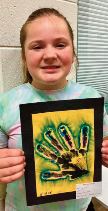 Elsie, Grade 4, created a mixed-media work titled Pop Art Hand Print. She began by applying black paint to her own hand, and making a handprint on the paper. She had to give it a couple tries to get the full hand print she was happy with. Once the handprint was set, she added an outline using oil pastels, then blended and softened the edges by pulling the paint outward with her fingers, creating a dynamic effect. Elsie chose a bright yellow background, which she feels works well with the blue around the edges.