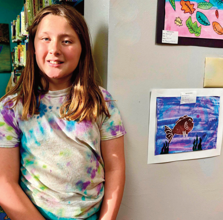 Natalie, Grade 4, created a mixed-media piece titled Japanese Fish Painting. The assignment introduced gyotaku, a traditional Japanese way of printing fish that was used by fishermen to prove the size of their catch. To begin, Natalie formed an outline of a fish and pressed it into a piece of foam. She used a roller to apply paint, then printed it onto paper. She chose a background of purple, pink, and blue, and printed the fish in red for strong contrast. Natalie is especially pleased with the colors and how much detail came through in the final fish print.