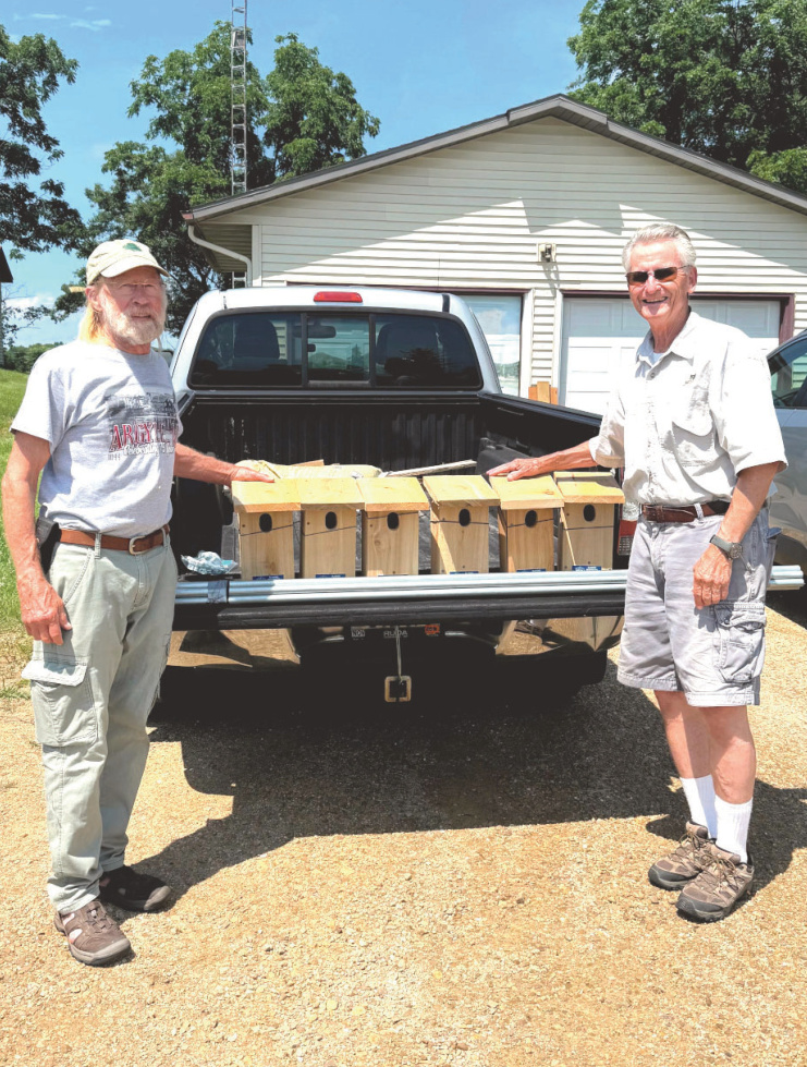 Two men standing by truck with 6 new bluebird nest boxes
